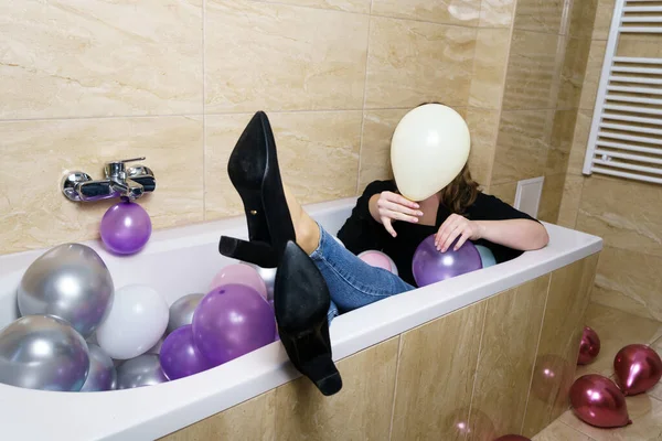 Banyodaki Balon dolu küvette oturan genç kadın.