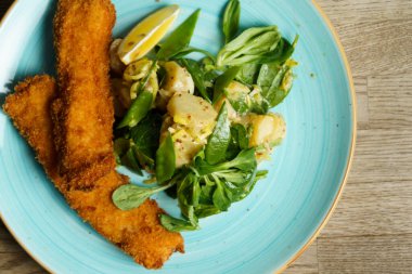 Kızarmış balık fileto patates salatası, dijon hardal ve bir dilim limon.