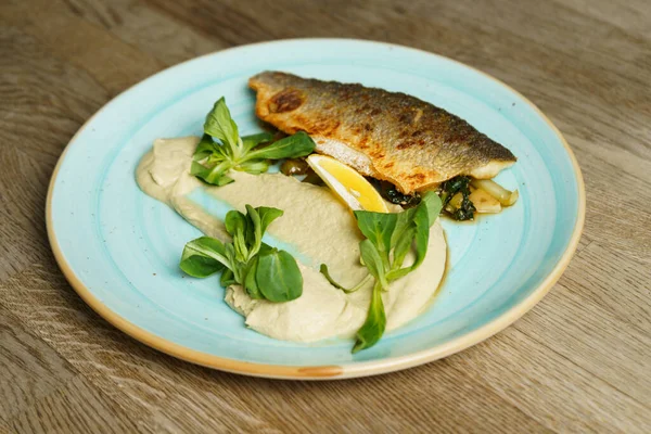 Kızarmış branzino balığı fileto enginar kreması ve susamlı kızarmış pak choi.