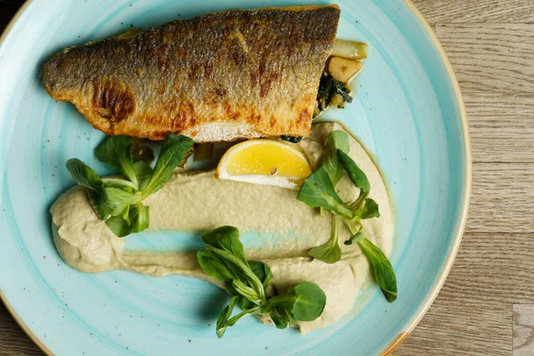 Kızarmış branzino balığı fileto enginar kreması ve susamlı kızarmış pak choi.