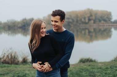 Gölün önünde birlikte duran romantik genç çift.