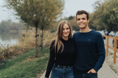 Parkta yürüyen neşeli genç çift