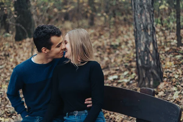 公園で若い陽気なカップル ボーイフレンドはガールフレンドにキスを与えます — ストック写真