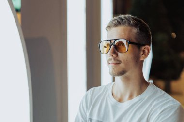 Gece vakti Neon Işıkları önünde güneş gözlüğü takan genç adam..