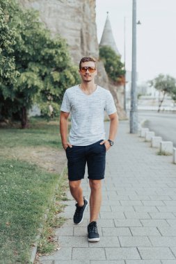Genç adam güneş gözlükleriyle yürüyor..