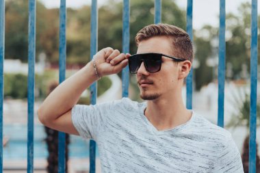 Güneş gözlüğünü tutan genç adamın portresi..