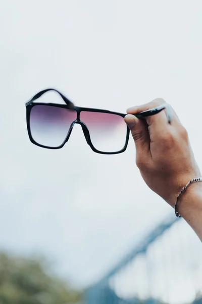 stock image Young Man Holding Sunglasses Against Sky.