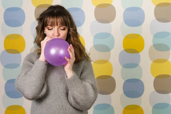 Young Woman Blowing a Purple Balloon