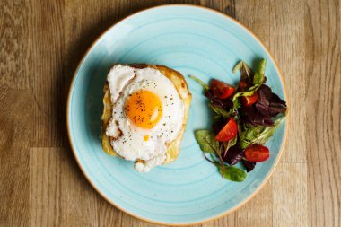 Peynirli ve jambonlu klasik Fransız tostu, kızarmış yumurta, sebze ve ballı sos..