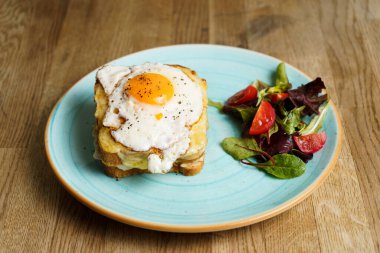 Peynirli ve jambonlu klasik Fransız tostu, kızarmış yumurta, sebze ve ballı sos..