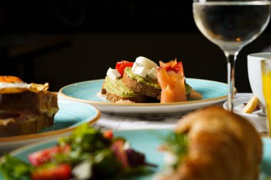 Avokado tostlu brunch masası guacamole, kaynamış yumurta, somon, krem peynir ve domatesli.