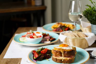Klasik Fransız tostu, peynirli ve jambonlu brunch masası, kızarmış yumurta, sebze ve ballı sos..