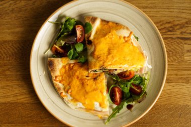 Jambonlu ve peynirli tortilla sandviçi ve ahşap masada sebzeler.