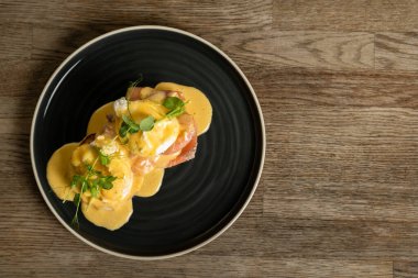 Tahta bir masada somonlu Benedict yumurtası.