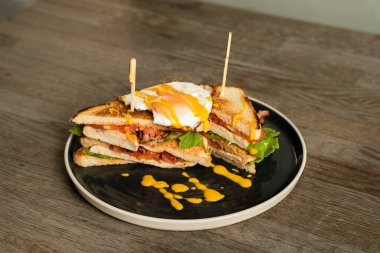 Kızarmış tavuklu kulüp sandviçi, kızarmış yumurta, sebze ve çedar peynirli sos.