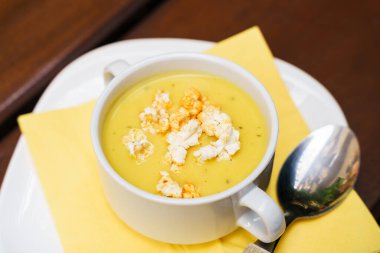 Tahta masada patlamış mısırlı bir kase tatlı mısır çorbası.