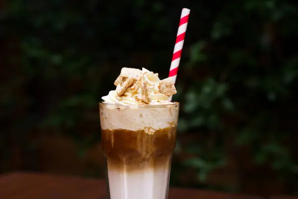 Iced coffee with cinnamon whip cream and a straw