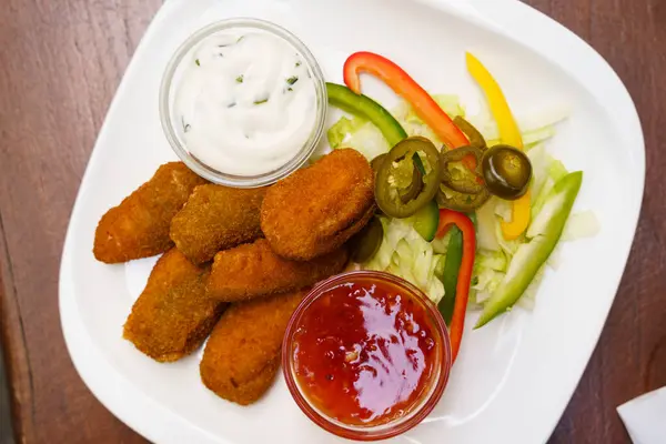 Chicken nuggets with salsa sauce, garlic sauce and vegetables