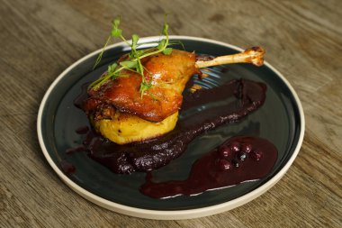 Patates püresi üzerine kızarmış ördek bacağı soğan, mor lahana kreması ve yabanmersini suyu.