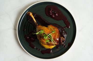 Patates püresi üzerine kızarmış ördek bacağı soğan, mor lahana kreması ve yabanmersini suyu.