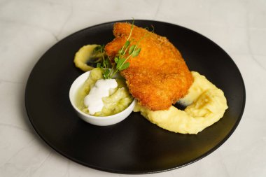 Şnitzel, kızarmış tavuk, salatalık salatası ve patates püresi.