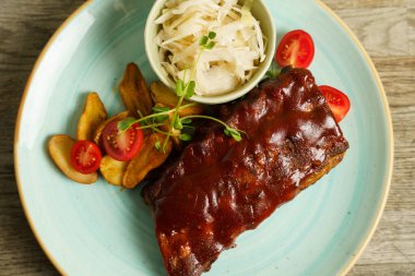 Biftek, patates ve lahana salatalı domuz pirzolası.