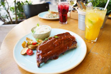 Biftek, patates ve lahana salatalı domuz pirzolası.