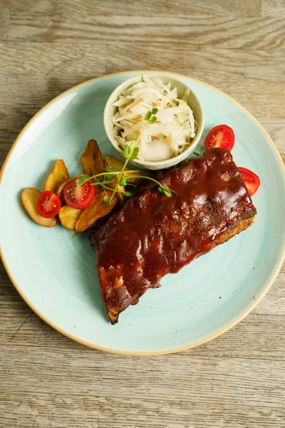 Biftek, patates ve lahana salatalı domuz pirzolası.