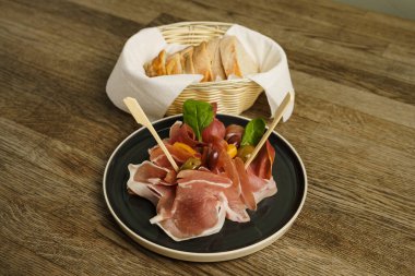 Jambonlu jambon, zeytin ve ahşap masada ekmek.