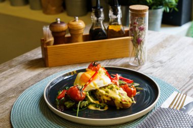 Avokado tostunun üstü kızarmış yumurta ve sebzeli.