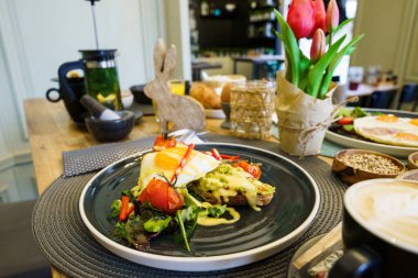 Brunch masasında kızarmış yumurta ve sebzeli avokado tostu.