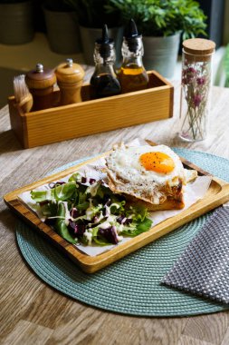 Croque Madam - Peynirli ve jambonlu klasik Fransız tostu, kızarmış yumurta, sebze ve ballı sos.