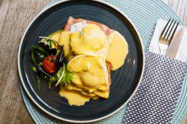 Tahta bir masada jambonlu Benedict yumurtası.