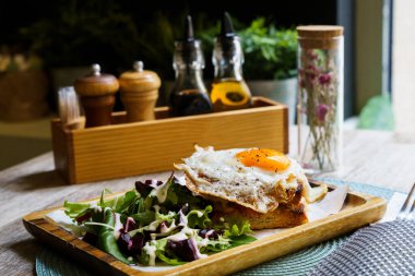 Croque Madam - Peynirli ve jambonlu klasik Fransız tostu, kızarmış yumurta, sebze ve ballı sos.