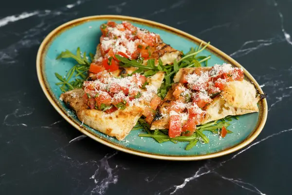 Domates, salata ve parmesan peynirli bruschetta dilimleri.