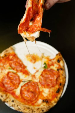 Erimiş peynirli bir dilim salamlı pizza.