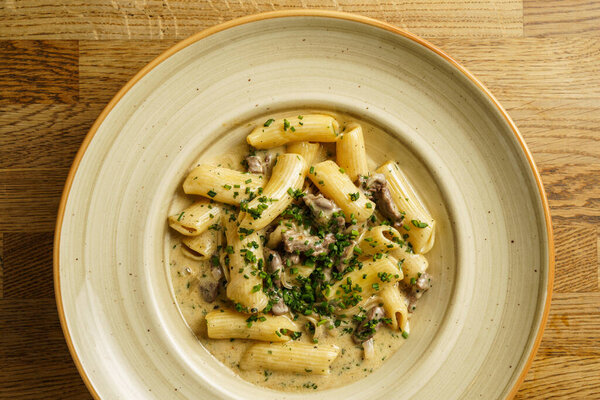 A plate of creamy pasta rigatoni, garnished with fresh herbs and filled with tender mushrooms. The rich, savory sauce complements the al dente pasta for a hearty meal.