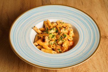 Kremalı domates sosuyla kaplanmış, doğranmış otlar ve lezzetli sosislerle süslenmiş doyurucu bir tabak makarna..