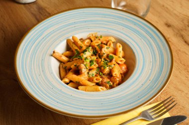 Kremalı domates sosuyla kaplanmış, doğranmış otlar ve lezzetli sosislerle süslenmiş doyurucu bir tabak makarna..