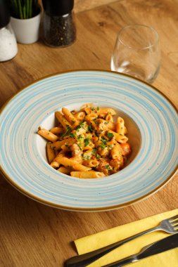 Kremalı domates sosuyla kaplanmış, doğranmış otlar ve lezzetli sosislerle süslenmiş doyurucu bir tabak makarna..