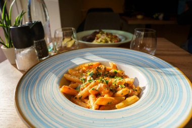 Kremalı domates sosuyla kaplanmış, doğranmış otlar ve lezzetli sosislerle süslenmiş doyurucu bir tabak makarna..