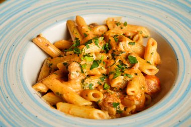 Kremalı domates sosuyla kaplanmış, doğranmış otlar ve lezzetli sosislerle süslenmiş doyurucu bir tabak makarna..