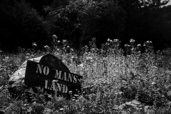 Wooden log sign saying no mans land in a flower meadow in england