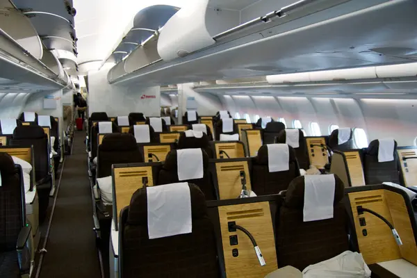 stock image ZURICH, SWITZERLAND - JUNE 22, 2019: Empty cabin with business class seats with wood applications and brown fabric in a long-haul aircraft on the flight from Dubai to Zurich.