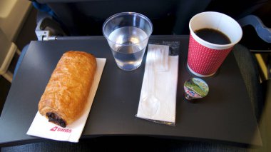 15 Nisan 2015 'te bir uçuş sırasında çekilen bu fotoğraf, uçakta servis edilen tipik bir kısa mesafe inflight kahvaltısını çekiyor. İçinde sıcak bir fincan eşliğinde bir peçeteye yerleştirilmiş çikolatalı kruvasan var.