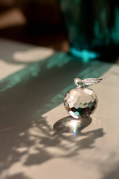 stock image Glamorous crystal apple with refraction of light and green vase on background 