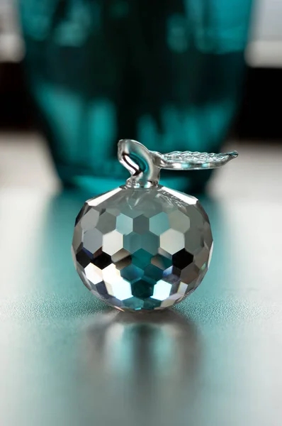 Glamorous crystal apple with refraction of light and green vase on background