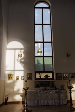 Kilisenin duvarındaki lamba ve ikonlar pencereden gelen güneş ışığıyla aydınlatılıyor. Tapınağın duvarındaki pencerenin gölgesi. Şifacı Aziz Panteleimon Kilisesi, Khmelnitsky, Ukrayna - 27 Kasım 2021 