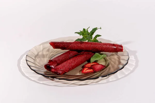 Fruit marshmallow. Strawberry pastille rolls and strawberry slice on a plate decorated with fresh mint isolated on white background. Healthy Eating. Healthy snacks. Sugar-free.