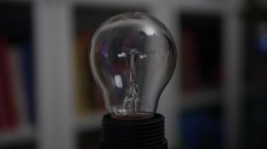 One Person Screws an Incandescent Light Bulb in the Socket and Turn On the Light in the Room. Wasting Energy Concept.